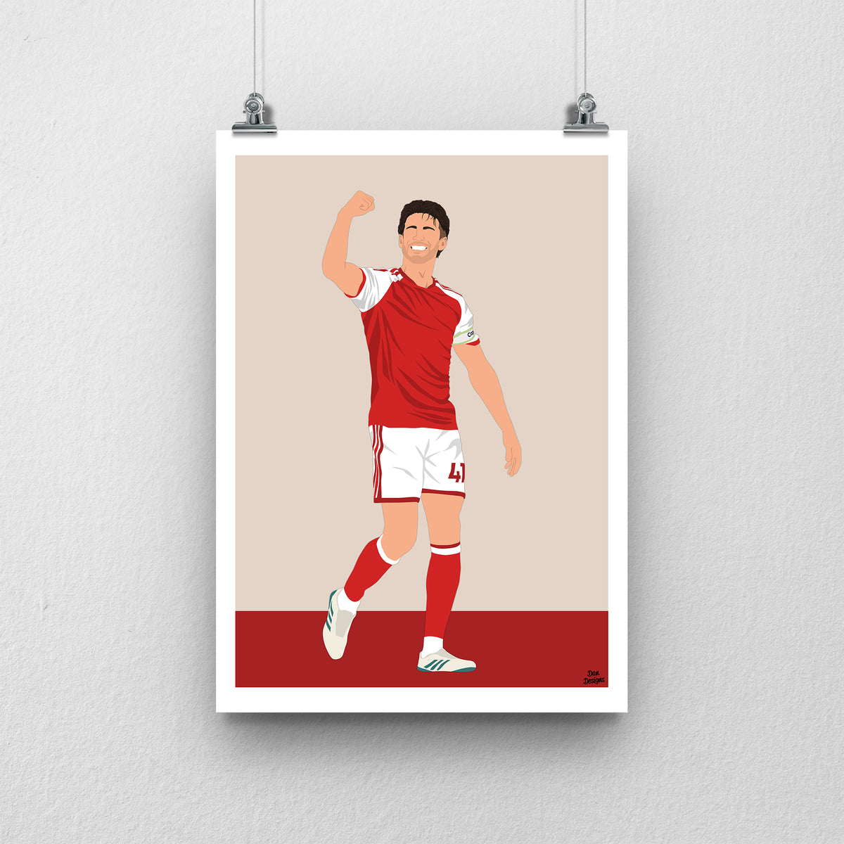 Declan Rice in Arsenal's red-and-white kit, celebrating with one arm raised and bent, against a beige background with a white border and red base.