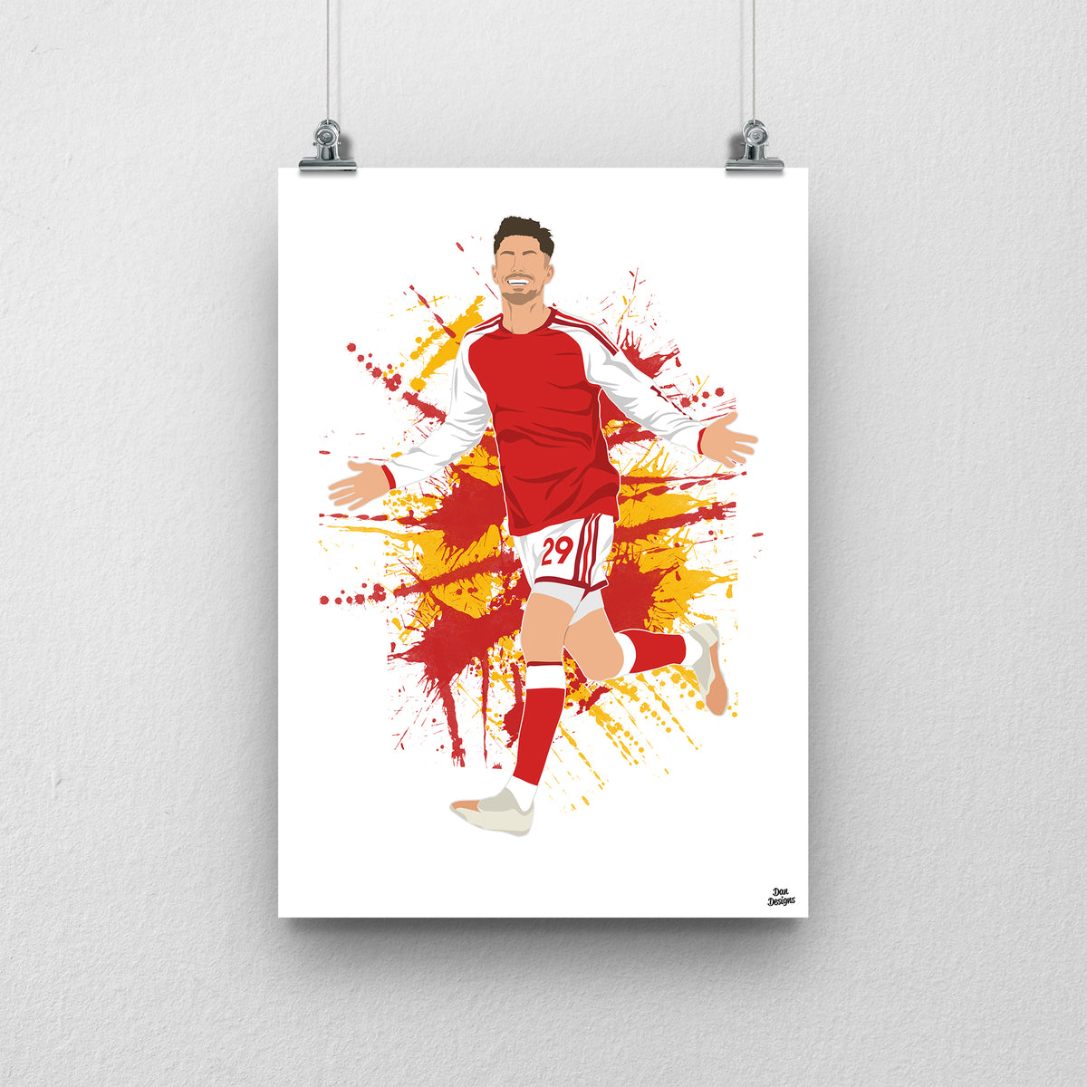 Kai Havertz running with both arms out in Arsenal's red shirt with white sleeves, against a red-and-gold paint-splatter background.