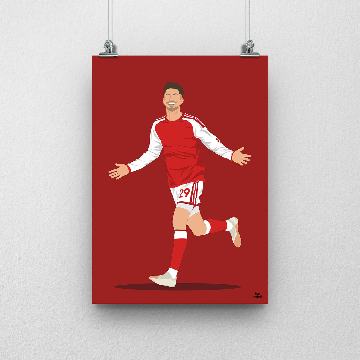 Kai Havertz running with both arms out in Arsenal's red shirt with white sleeves, against a red background.
