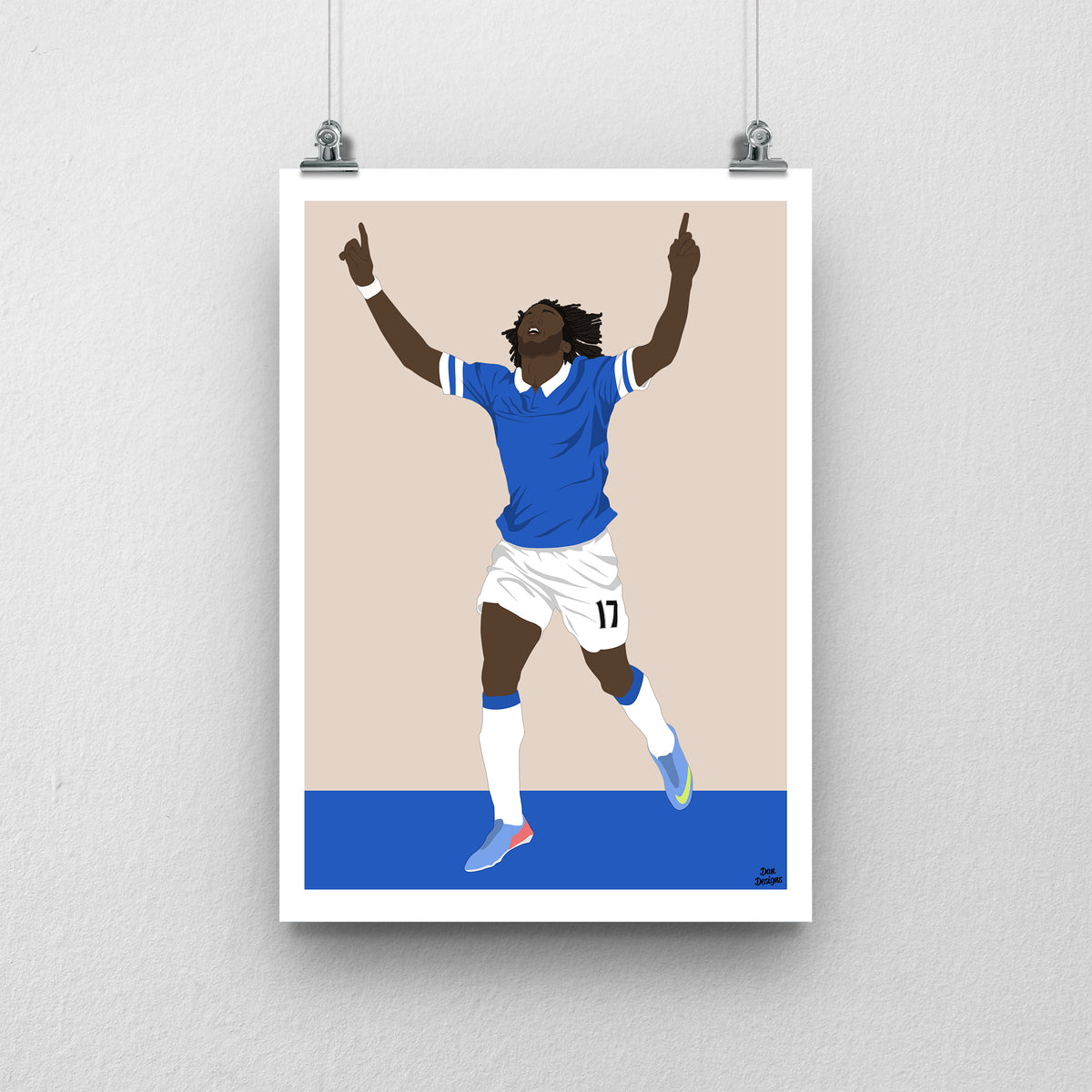 Romelu Lukaku Everton print, celebrating with both index fingers pointing upwards in the blue Everton kit, with a beige and blue design and white border.